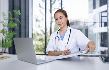 Smiling Female Doctor with Clipboard and Laptop for Online Medical Consultation working in Modern Clinic.