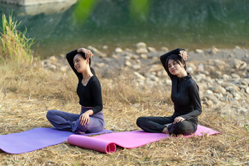 Asian Indonesian women stretching during outdoor yoga by the river in tropical nature
