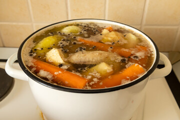 Homemade chicken broth with vegetables in white pot © Sarolta Nagy
