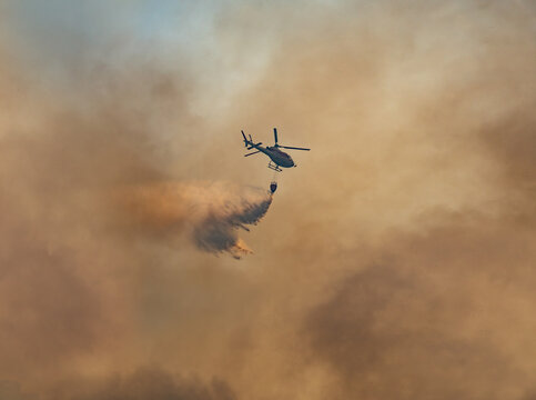 Fire fighting helicopter carry watethar bucket to extinguish the forest fire.