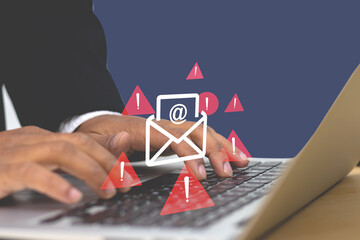 Hands typing on a laptop with red warning icons and an email fishing alert symbol, representing...