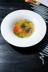 Clear broth with eel pieces, carrots, tomatoes, and herbs. Traditional eel soup served at a local open-air restaurant near Lake Svityaz, Ukraine. Culinary heritage of Polissya.