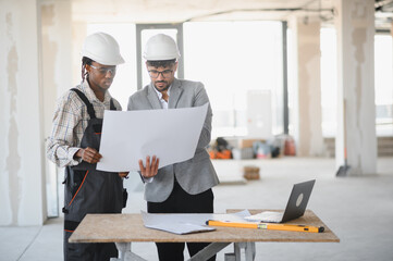 Architect and builder reviewing blueprints on construction site