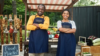 Zooming in on African American couple wearing aprons, crossing hands and cheerfully smiling on...