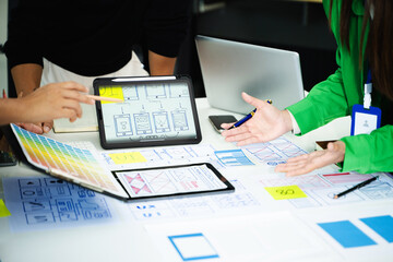 Creative team collaborating on UX/UI wireframe designs for a mobile app. Hands on planning,...