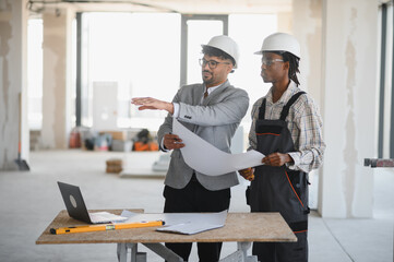 Architect showing blueprint to builder during construction meeting