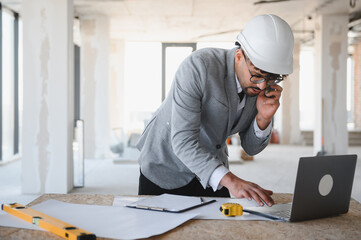 Arab architect managing construction project using laptop and smartphone