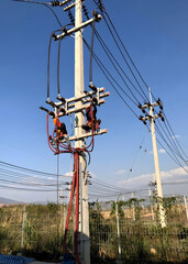Vertical shot of the electricians working on the electric post power pole for the power cable installation.