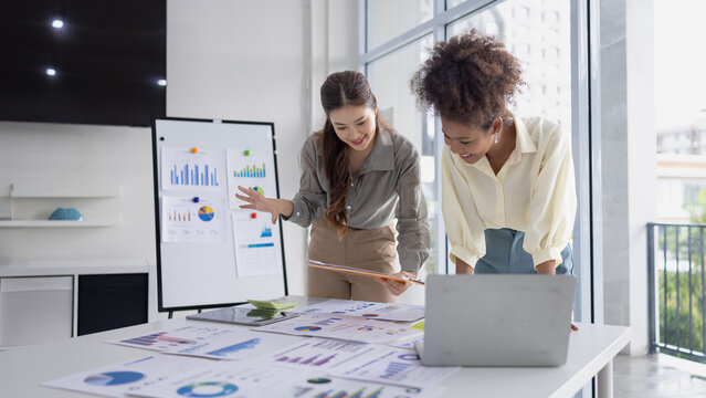 Two business woman working together for analysis data plan business strategies at desk in office, Business discussing and startup concept.
