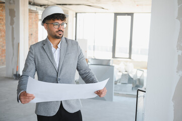 Architect inspecting blueprint on construction site of modern building