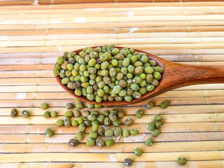 mung beans in a wooden spoon on bamboo mat