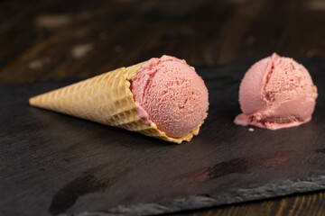 melting pink ice cream on a black slate board, sweet cold pink ice cream with strawberry flavor,...