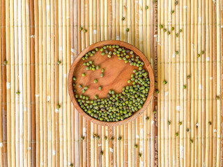 flat lay of mung bean in a wooden bowl on bamboo mat