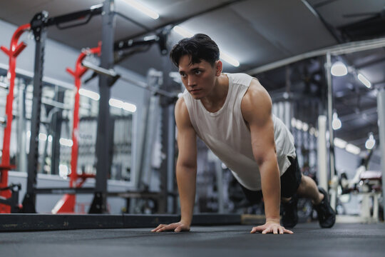 Determined asian athlete doing push ups in modern gym