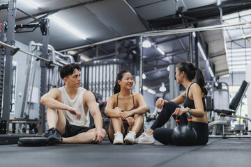 Fitness people relaxing and talking on gym floor