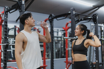 Young couple rehydrating and showing muscles at the gym