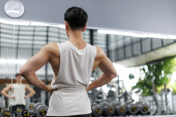 Bodybuilder showing back muscles in fitness center mirror
