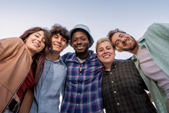 Multiracial young friends smiling and bonding outdoors in sunny day