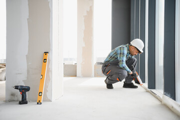 Construction worker sealing windows in building under construction