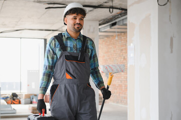 Arab engineer holding paint roller and toolbox on construction site