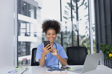 African American female doctor using mobile phone with laptop working at clinic office, Medical and health care concept.