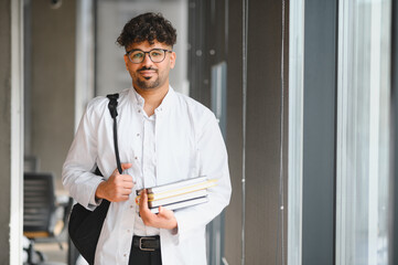Arab medical student carrying books in university hallway