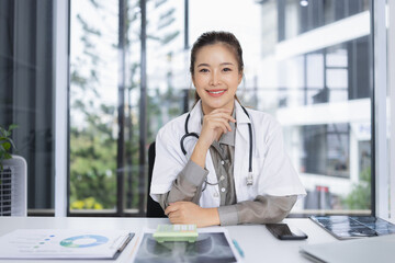 portrait of a confident female doctor sitting at working desk in  hospital, Medical and health care concept.