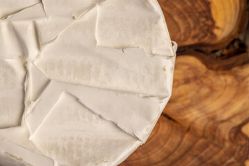 soft white cheese covered with white mold on the table, round-shaped processed cheese in white edible mold