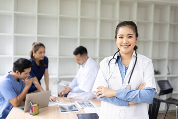 A young female doctor smiling looking at the camera in meeting room, Medical team reviewing data.
