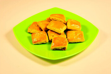 A close-up of golden-brown pineapple nastar cookies, beautifully arranged on a green plate. The cookies' glossy surface and crumbly texture make them irresistibly appetizing.