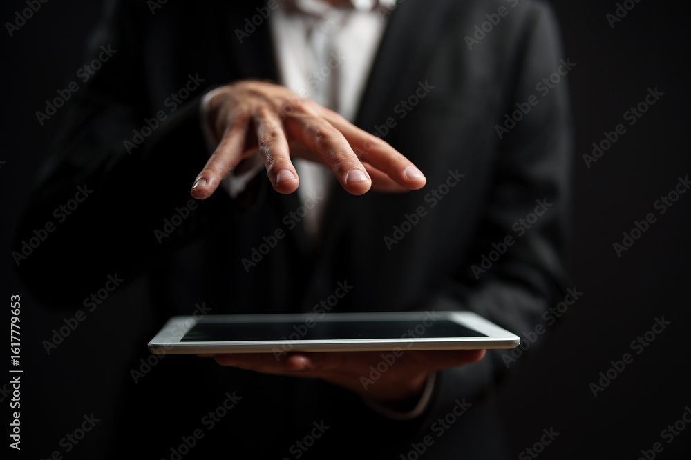 Poster professional man using tablet with fingers hovering over screen in dark background