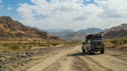 Off road vehicle driving through a desert landscape with mountains and a cloudy sky in the background