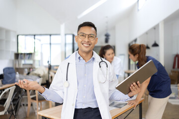 A male doctor smiling looking at the camera in meeting room, Medical team reviewing data.