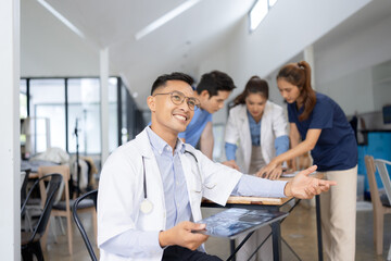 Obraz premium A male doctor smiling looking at the camera in meeting room, Medical team reviewing data.