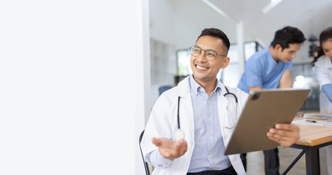 A male doctor smiling looking at the camera in meeting room, Medical team reviewing data.