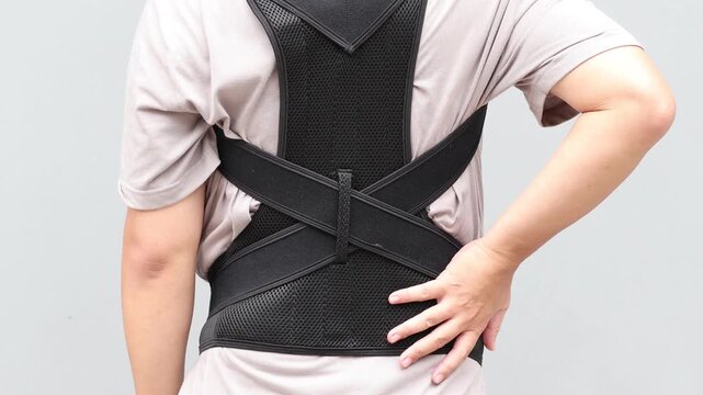 Young asian man wearing a back support belt, Lumbar brace for back trauma or Herniated Disc To relieve back pain. background