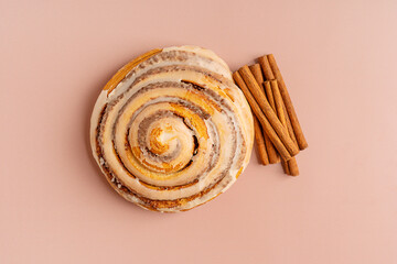 Top view of single delicious homemade sweet cinnamon roll bun or swirl glazed with sugar icing with...