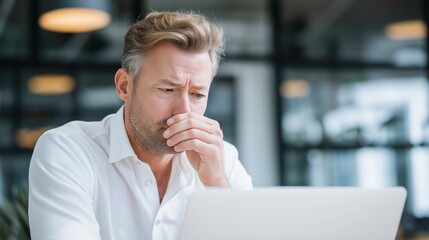 Pensive Man Working on Laptop in Modern Office