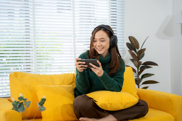 Cozy Gaming Moments: A woman immersed in her mobile game while sitting on a comfortable sofa and...