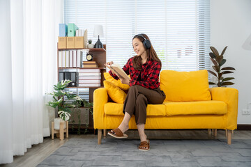Cozy Comfort: A woman immersed in her world, listening to music while relaxing on a yellow sofa....