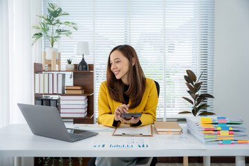 Focused at Work: A woman concentrating on her work, using a calculator and computer, creating a...