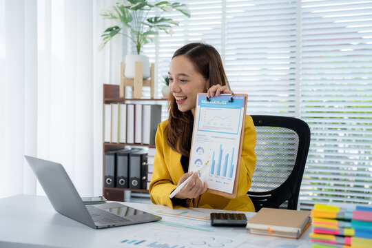 Online Business Presentation: A confident businesswoman in a stylish suit enthusiastically presents financial data during a video call from a modern office.