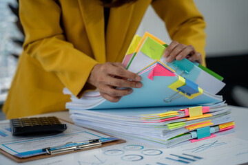 Organized Filing: A diligent professional meticulously organizes a pile of color-coded documents,...