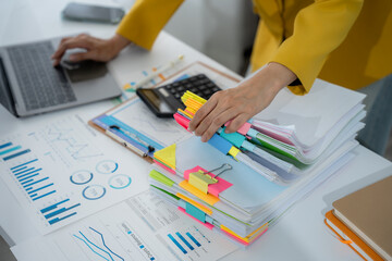 Focused Work: A person's hands busy amidst a clutter of financial documents, laptop, and office...