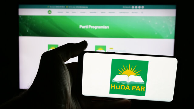 Stuttgart, Germany - 07‑23‑2025: Person holding mobile phone with logo of Turkish party Hur Dava Partisi (Huda Par) on screen in front of web page. Focus on phone display.