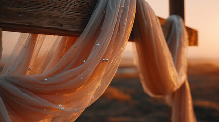 Draped sheer fabric with pearls hanging on wooden frame at sunset  