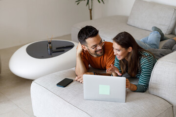 Man and woman use credit card and laptop for online shopping at home