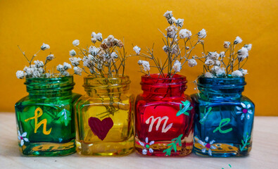 Flowers in colorful glass jars, forms the word HOME 