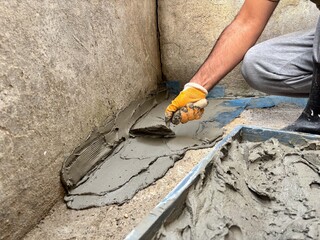 Manual Laborer Applying Wet Cement with a Trowel on a Foundation
