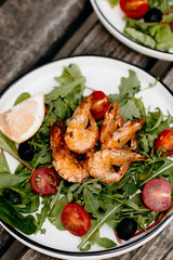 Gourmet arugula salad with grilled king prawns, lemon slices and olives, Mediterranean style meal